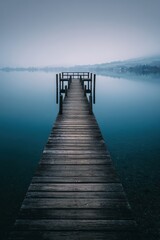 Fototapeta premium Long wooden jetty reaching across a calm lake, balanced composition