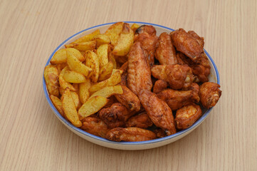A platter of baked fries with a crispy crust and golden chicken wings