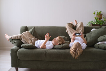 kids boys twins using smartphones lying on the couch