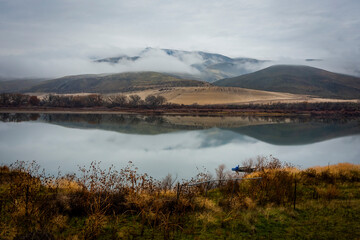 Beautiful foggy landscape in late autumn. Low clouds and riverbanks reflected in calm water of the Snake River in eastern Oregon