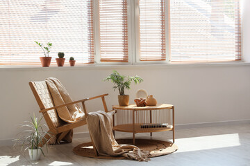 Interior of living room with wooden wicker armchair, coffee table and houseplants on windowsill