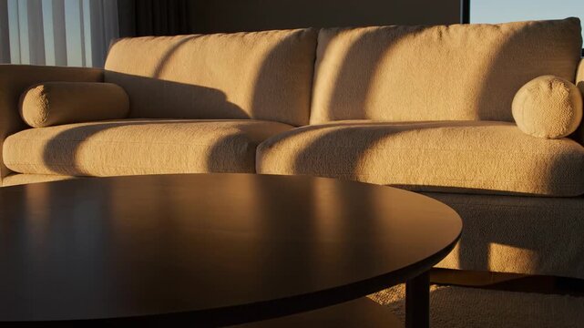 Abstract time-lapse showing soft geometric shadows slowly sweeping across the sleek round coffee table and adjacent upholstered sofa throughout the day clean aesthetic, movement, passing hours