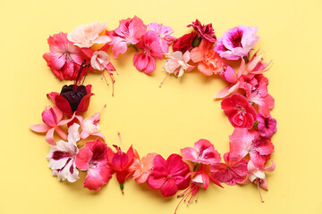 Frame made of different beautiful edible flowers on yellow background