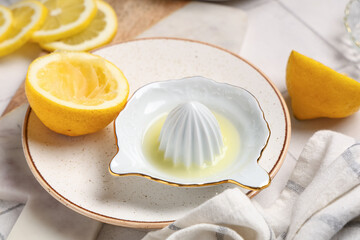 Composition with plate, ceramic juicer with lemon juice on white tile background, closeup