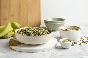 Bowls with cardamom spice and powder on grey table