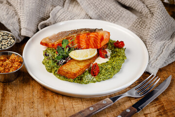 Grilled salmon served on a green puree with garnish