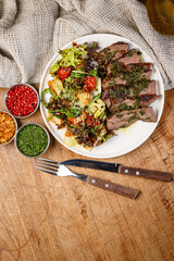 Grilled meat with salad served on a wooden table