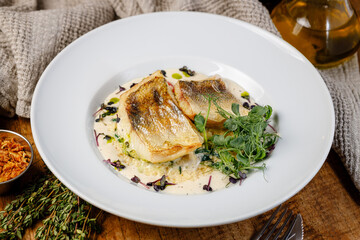 Fresh fish dish served with herbs and sauce on a white plate