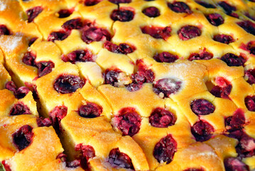 Sheet cake with cherries cut into individual serving squares for crowd service. Represents nostalgic home baking, traditional fruit desserts, celebration sweets, seasonal flavors, and homemade treats.