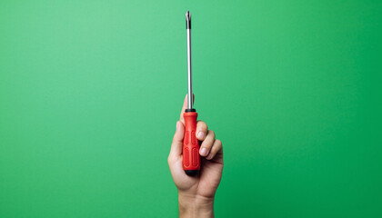 Hand Holding Red-Handled Screwdriver Upward Against Solid Green Background - Tool Showcase in Minimalist Environment