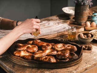 In a traditional Romanian kitchen, warm steam rises from a clay oven as freshly baked colaci and mucenici await. The rustic interior, filled with natural light, exudes village charm and authenticity