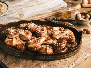 Inside a traditional Romanian kitchen, a wood-fired stove emits warmth as freshly baked golden mucenici and braided colaci rest on a wooden table, surrounded by an authentic village atmosphere