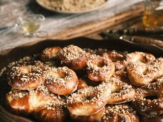 In a traditional Romanian kitchen, a wood-fired stove warms the space as freshly baked mucenici cool on an old wooden table. The village atmosphere is complete with soft light and aromatic steam