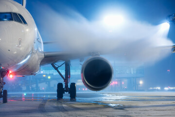 De-icing airplane shortly before take off. Freezing winter night at snowy airport.