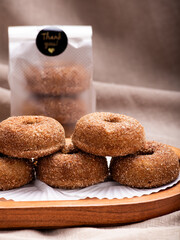 A delectable stack of freshly baked cinnamon sugar donuts presented on a rustic wooden tray.
