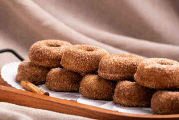 A delectable stack of freshly baked cinnamon sugar donuts presented on a rustic wooden tray.