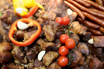 Different type of grilled soussage and pork meat prepared on grill at a Christmas market where various traditional dishes are served.

