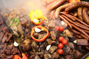 Different type of grilled soussage and pork meat prepared on grill at a Christmas market where various traditional dishes are served.
