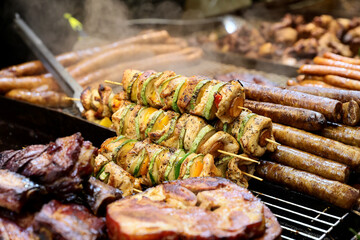 Grilled chicken kabobs prepared on grill at a Christmas market where various traditional dishes are served.

