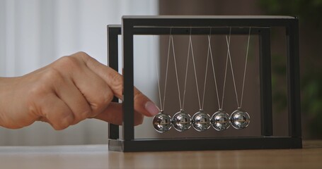 Close up of Hand Interacting with Newton Cradle