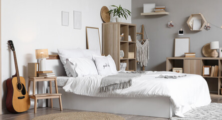 Interior of light teenager's room with bed, guitar and bookshelves © Pixel-Shot