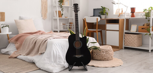 Interior of light bedroom with guitar and workplace