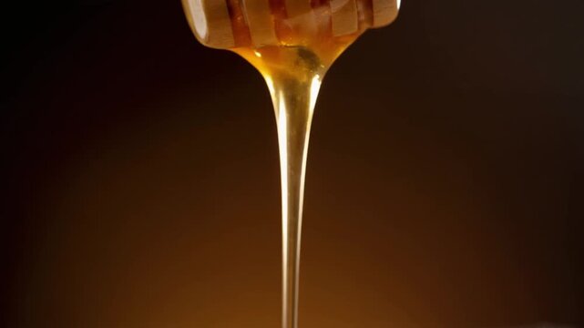 Extreme close-up of thick honey dripping slowly from a wooden dipper, golden reflections, dark warm background