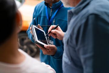 Person uses tablet to collect information in outdoor setting during daytime with another person...