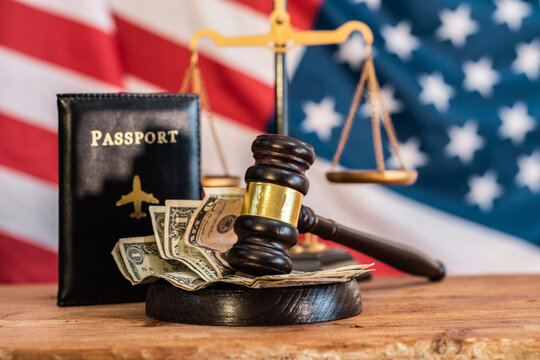 A judge's gavel, money, and a passport placed together against the backdrop of the American national flag. Immigration law. The cost of citizenship. American Independence Day. Illegal documents. fine - Powered by Adobe