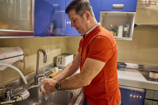 A middle-aged man at home in the morning makes coffee and serves it. - Powered by Adobe