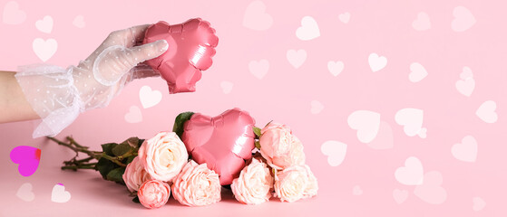 Female hand in mesh glove, rose flowers and heart-shaped balloons on pink background. Valentine's Day celebration