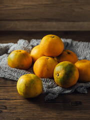 Fresh oranges on rustic wooden table with textured cloth backdrop