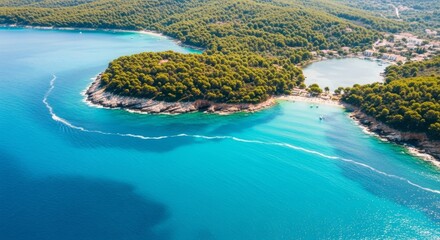 Aerial view of pristine coastline with turquoise waters, lush green forests, boats and buildings.