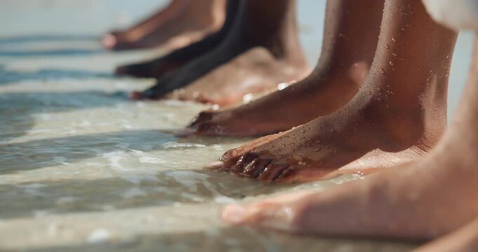 Friends, feet and relax at beach with waves for summer holiday, travel and bonding on weekend break. People outdoor, toes and together in ocean water for tropical vacation, wellness and connection.