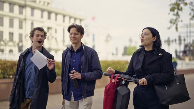 Three young friends engage in a dynamic conversation on a city street, with one gesturing animatedly and another holding an electric scooter.