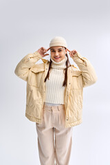 Trendy teenage girl styled in cozy winter fashion in a bright studio setting