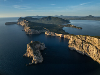 Aerial view of dramatic limestone cliffs plunge into the turquoise sea near Capo Caccia, creating a stunning contrast of natural beauty, Alghero, Sardinia, Italy.