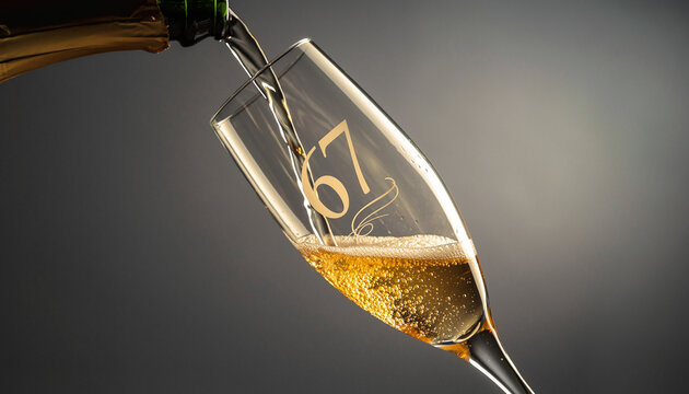 Glass engraved with the number 67. Champagne bottle fills the glass with alcohol. Celebrating milestone, anniversary or birthday