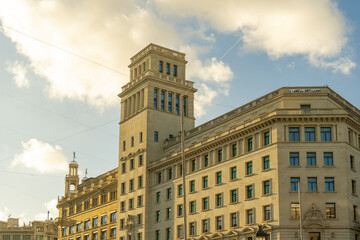 View of warm sunlight bathes the ornate, multi-story building with its symmetrical windows and tower reaching towards the blue sky, Barcelona, Catalonia, Spain.