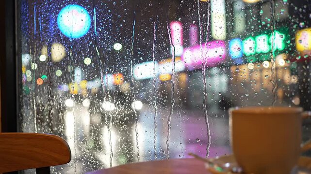 Raindrops on cafe window with city lights reflection