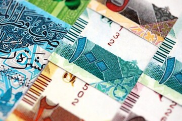 Qatari riyal money bills banknotes lies in big pile on table close up. Concept of finances and business in Qatar