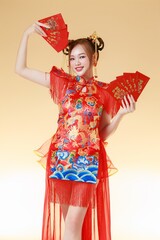 Happy Asian Woman Holding Red Envelopes and Fan. Fashionable female model in Modern Qipao with Ang Pao.