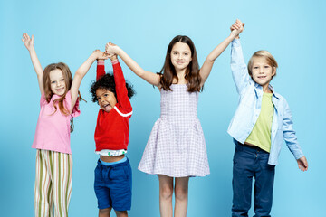 Fototapeta premium Diverse children friends holding hands forming a team on a blue background
