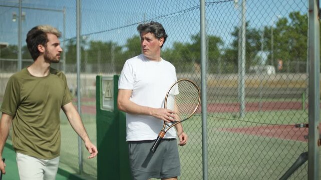 Father and son leaving a tennis court after playing a match