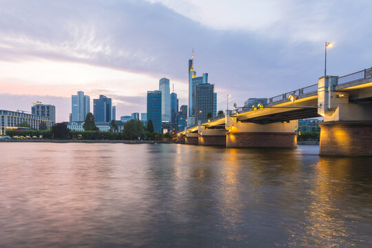 View of the Main River reflecting the city skyline and bridge lights, as dusk settles over the financial district, Frankfurt am Main, Hessen, Germany.