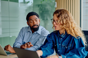 Diverse professionals discussing project and working together at desk in modern office. Teamwork and business communication concept