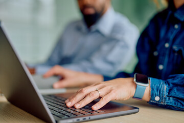 Close-up of a person's hand typing on a laptop keyboard during a business meeting, collaborating with a colleague