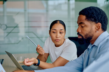 Two diverse business people collaborating, analyzing data and discussing strategy in a modern office meeting, focusing on shared goals
