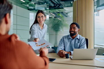 Diverse business professionals conducting a collaborative meeting, sharing reports and planning strategies in a modern office environment