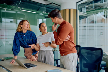 Three colleagues engaged in a lively discussion at office, sharing insights and working together on...
